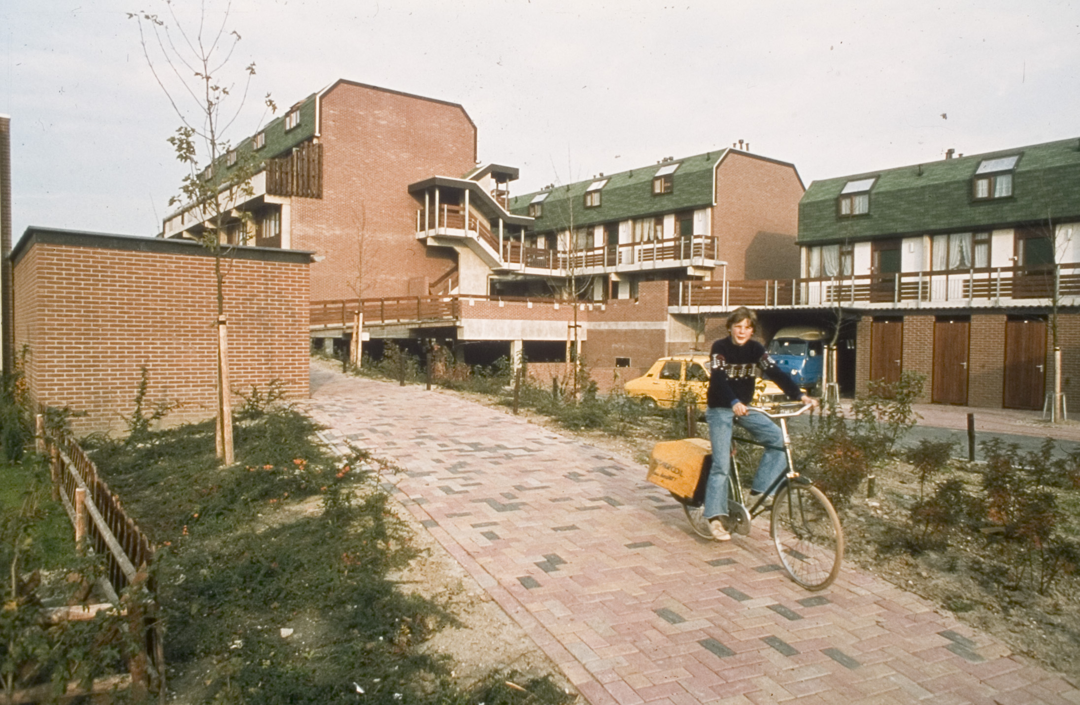 Krantenbezorger met fiets bij de woondekken in de rodenbuurt in Buytenwegh